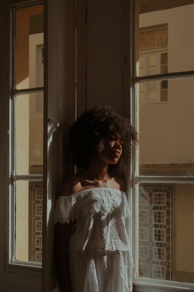 Young black woman in a white dress staring out of a window, Therapy for Life LLC